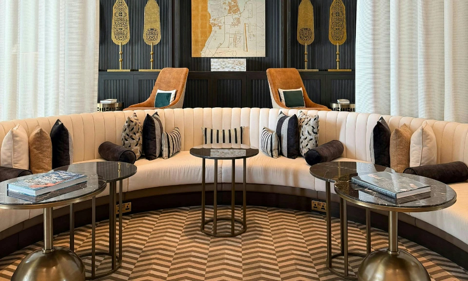 Salon élégant : canapé courbe, bibliothèque murale, lustres dorés et tapis à motifs géométriques.