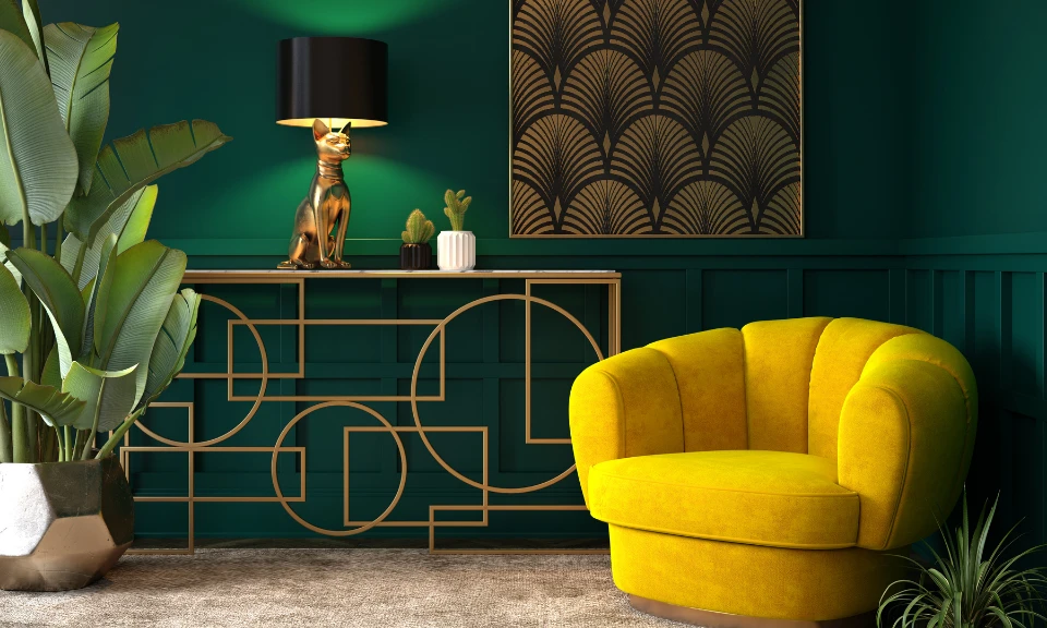 Intérieur Art Déco : mur vert émeraude, fauteuil jaune vif, console dorée géométrique, lampe chat et tableau motif éventail.