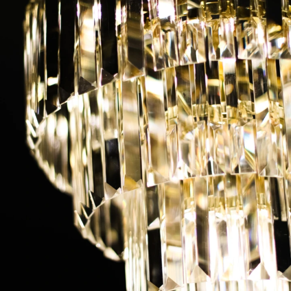 Gros plan sur des prismes de cristal suspendus brillant sur fond noir.